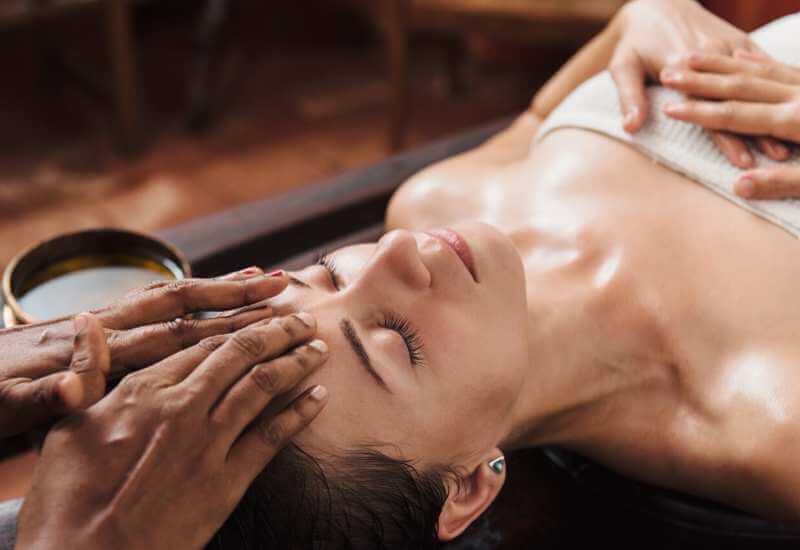 Mujer recibiendo masaje en la frente como parte de un facial con relajante.